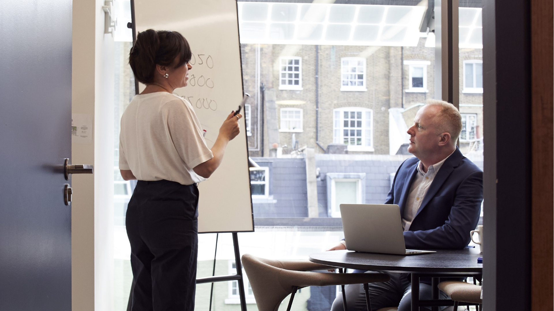 A male and female real estate agent discussing their real estate marketing plan in a conference room