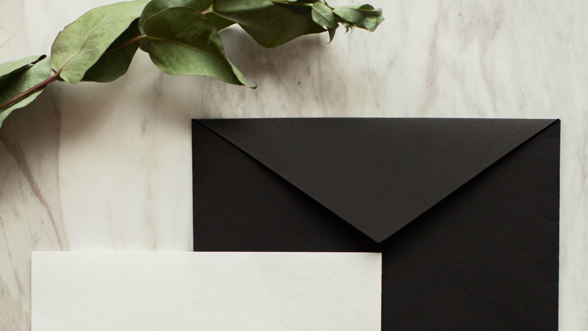 Image of a black envelope and small white postcard laying on table