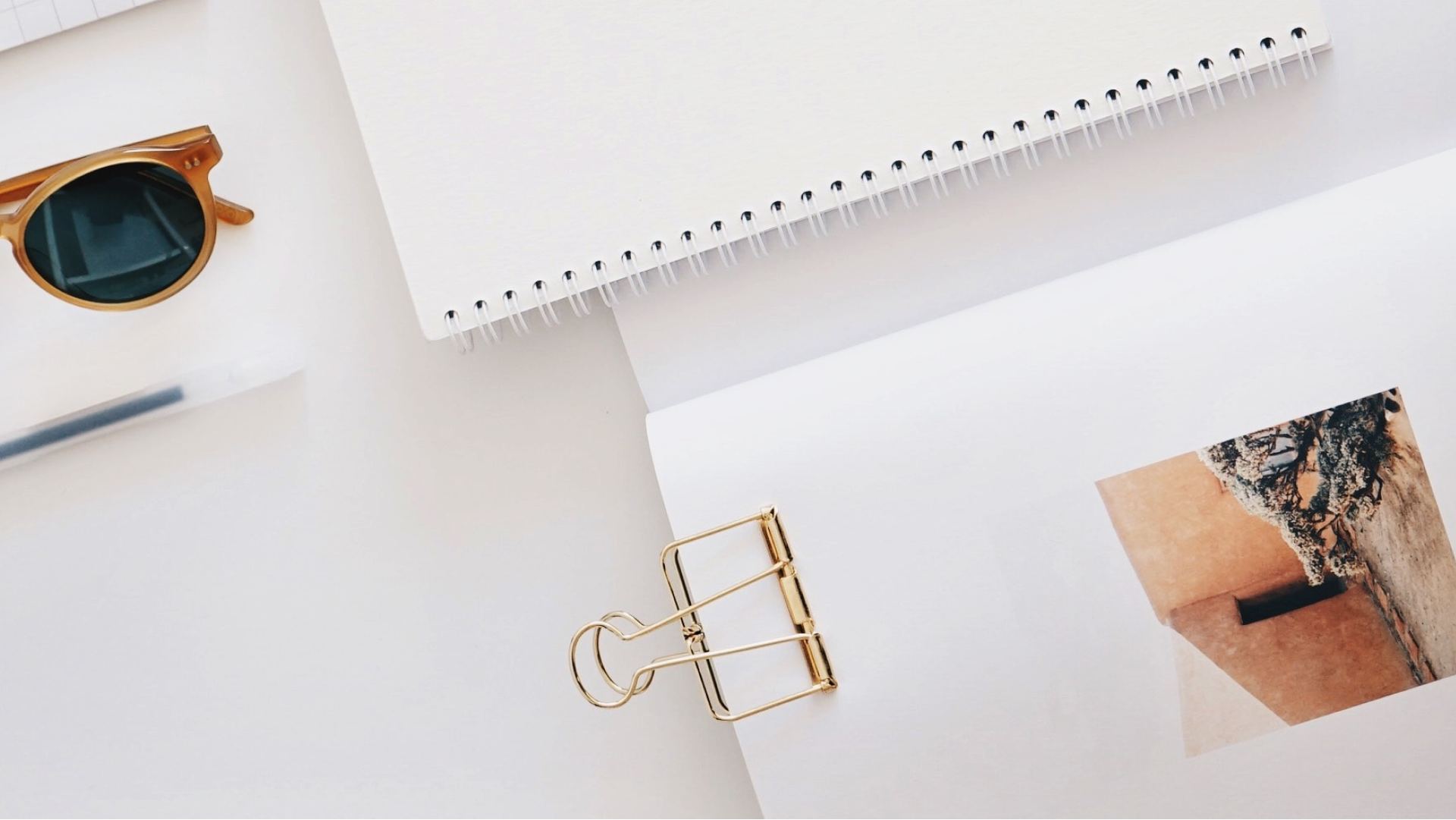 image of a notebook and clipboard sitting next to sunglasses on a desk