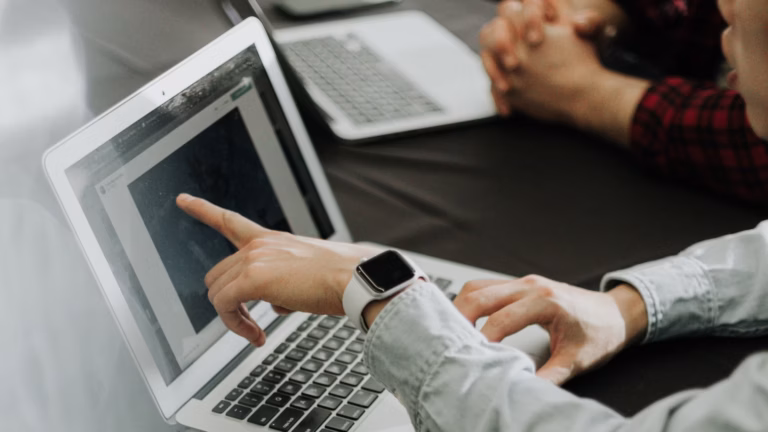 real estate agent sitting at desk pointing at laptop screen