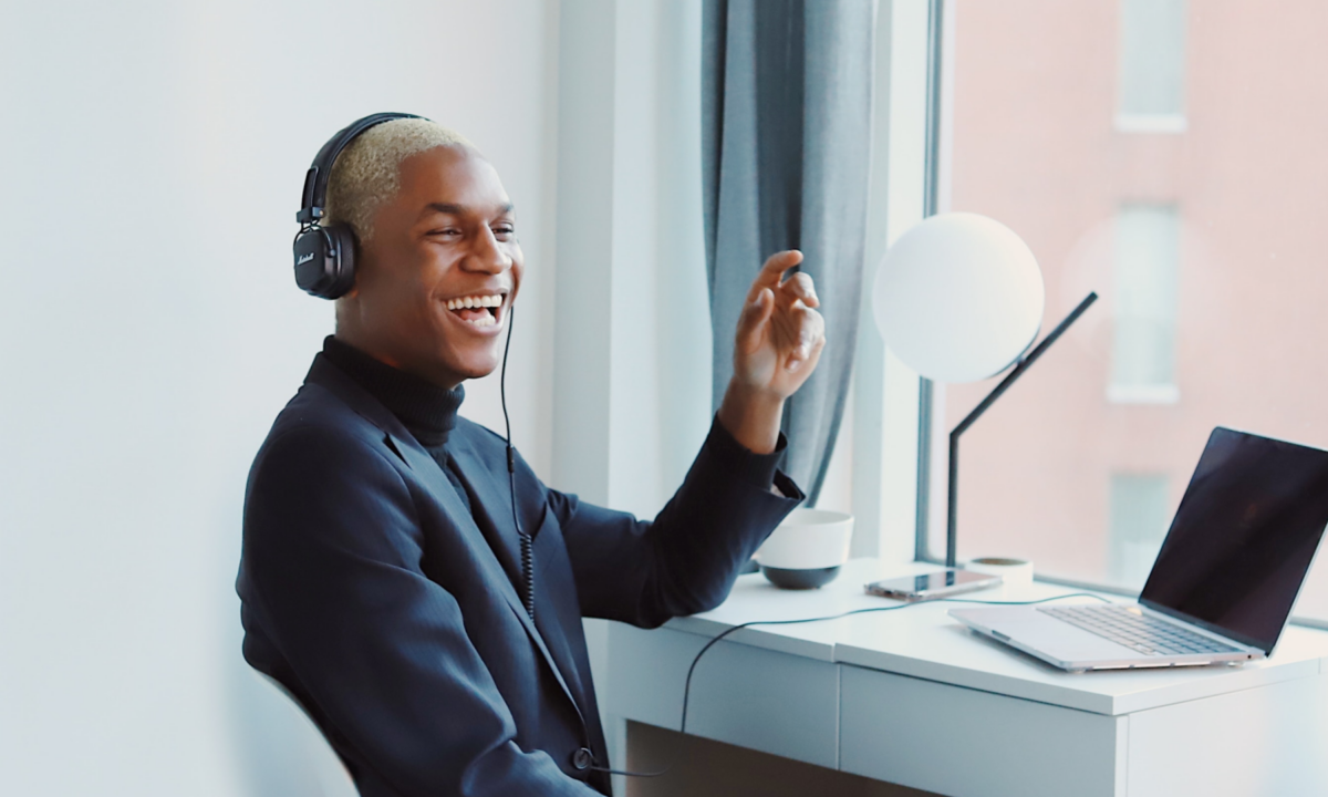 Young African-American SEO expert sitting at desk with headphones on advising a real estate agent client on Google's top ranking factors they should consider for their real estate website