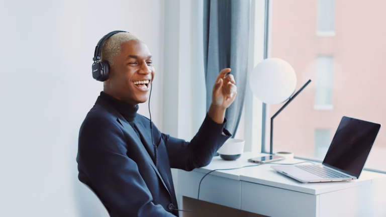 Young African-American SEO expert sitting at desk with headphones on advising a real estate agent client on Google's top ranking factors they should consider for their real estate website