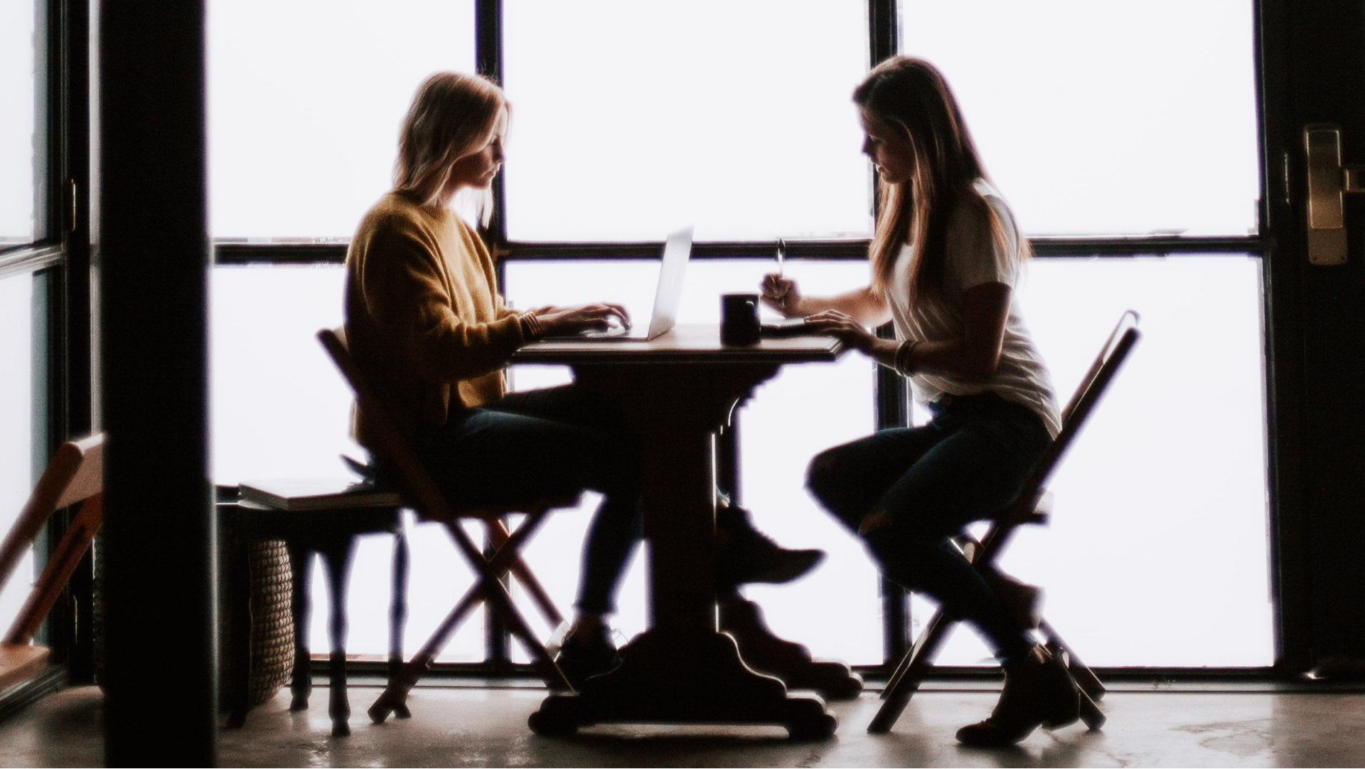 two female real estate agents sitting at table in coffee shop working