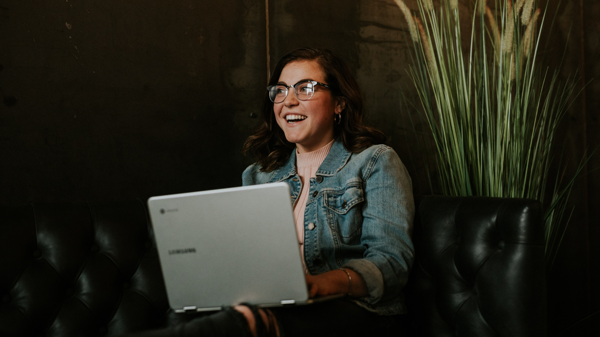 young professional SEO specialist wearing glasses, holding laptop in hand at a coffee shop