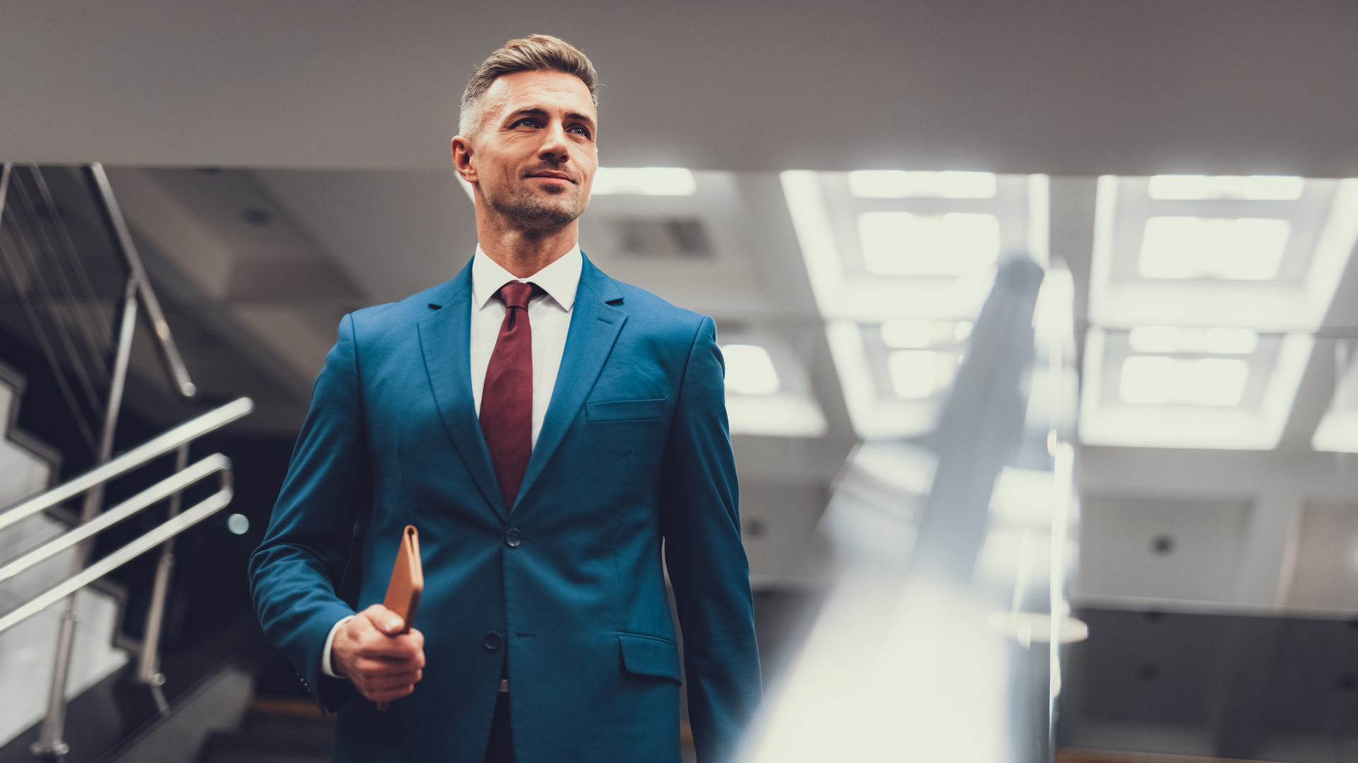 Image of male real estate agent standing confidently with notebook in hand