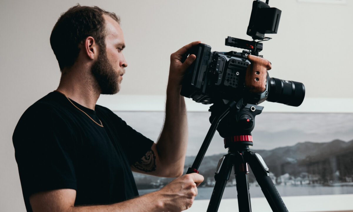 photographer wearing a black shirt using camera and tripod to demonstrate how to take real estate photos