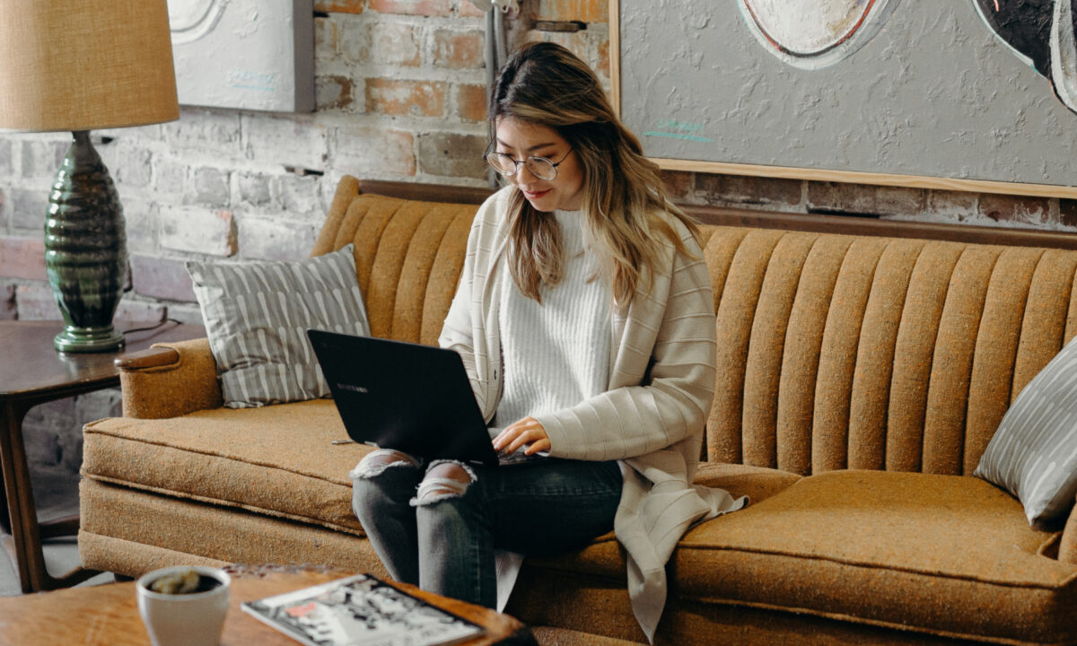 agent sitting on couch reading blog on laptop about real estate email marketing