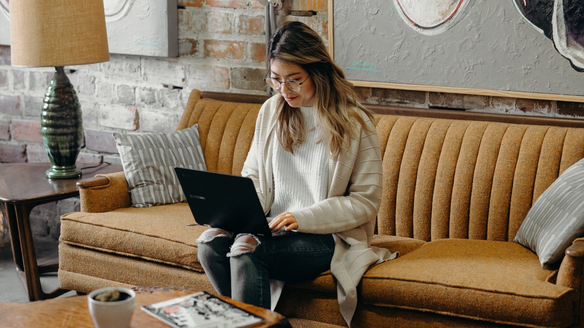 agent sitting on couch reading blog on laptop about real estate email marketing