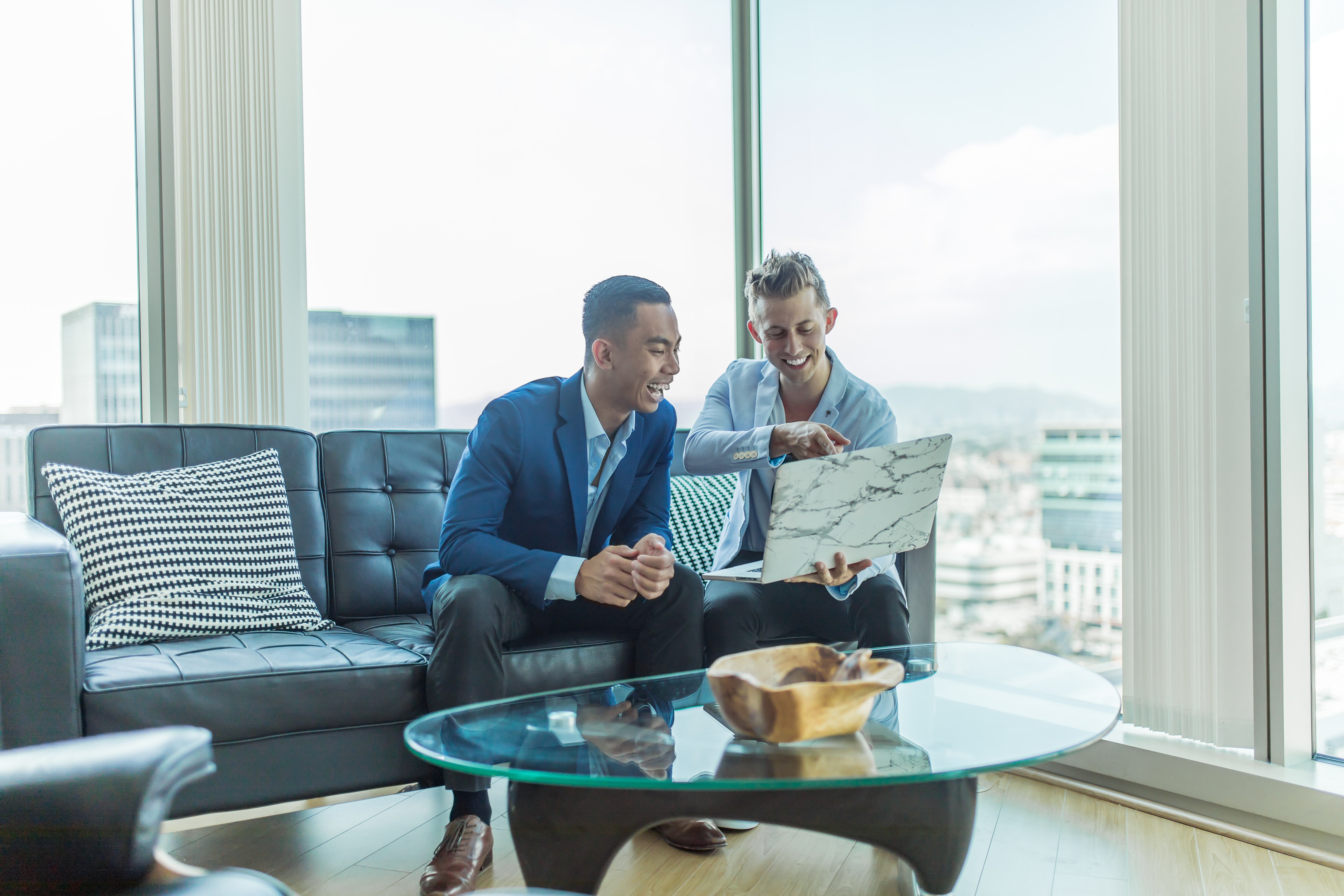 two agents looking at laptop and laughing in apartment