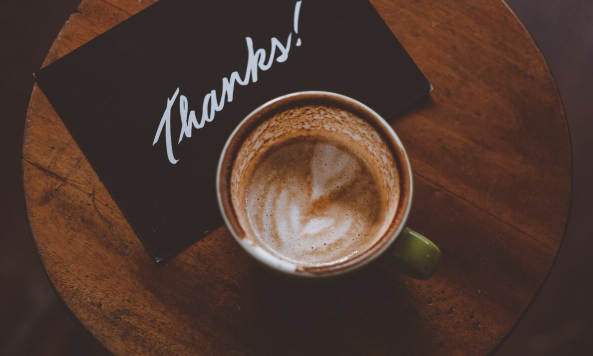a black thank you card sits next to a coffee cup illustrating one option for real estate pop by ideas