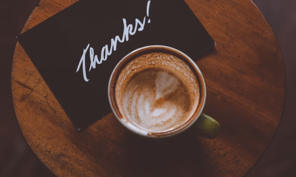 a black thank you card sits next to a coffee cup illustrating one option for real estate pop by ideas