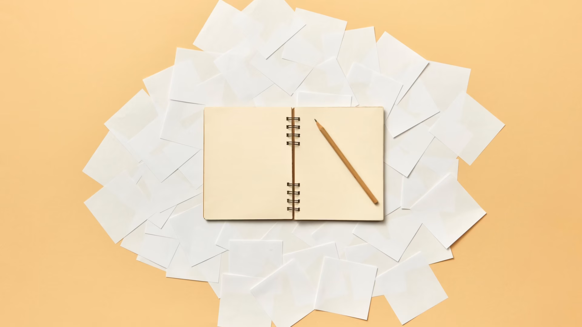 A pencil sits on top of a blank book where an agent is coming up with real estate words and creative real estate listing descriptions examples for their marketing