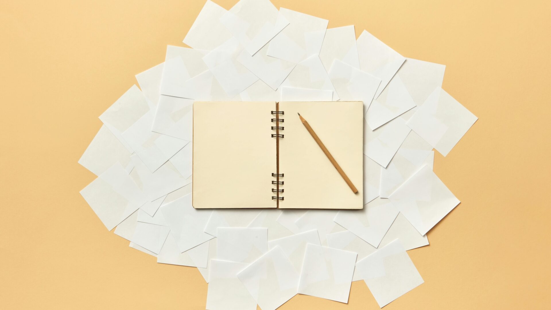 A pencil sits on top of a blank book where an agent is coming up with real estate words and creative real estate listing descriptions examples for their marketing