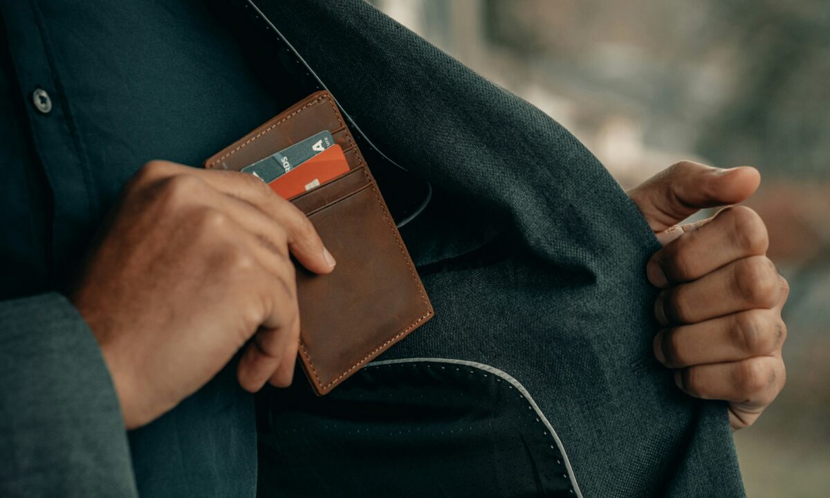 A broker places his wallet in his suit coat pocket, representing his real estate broker salary