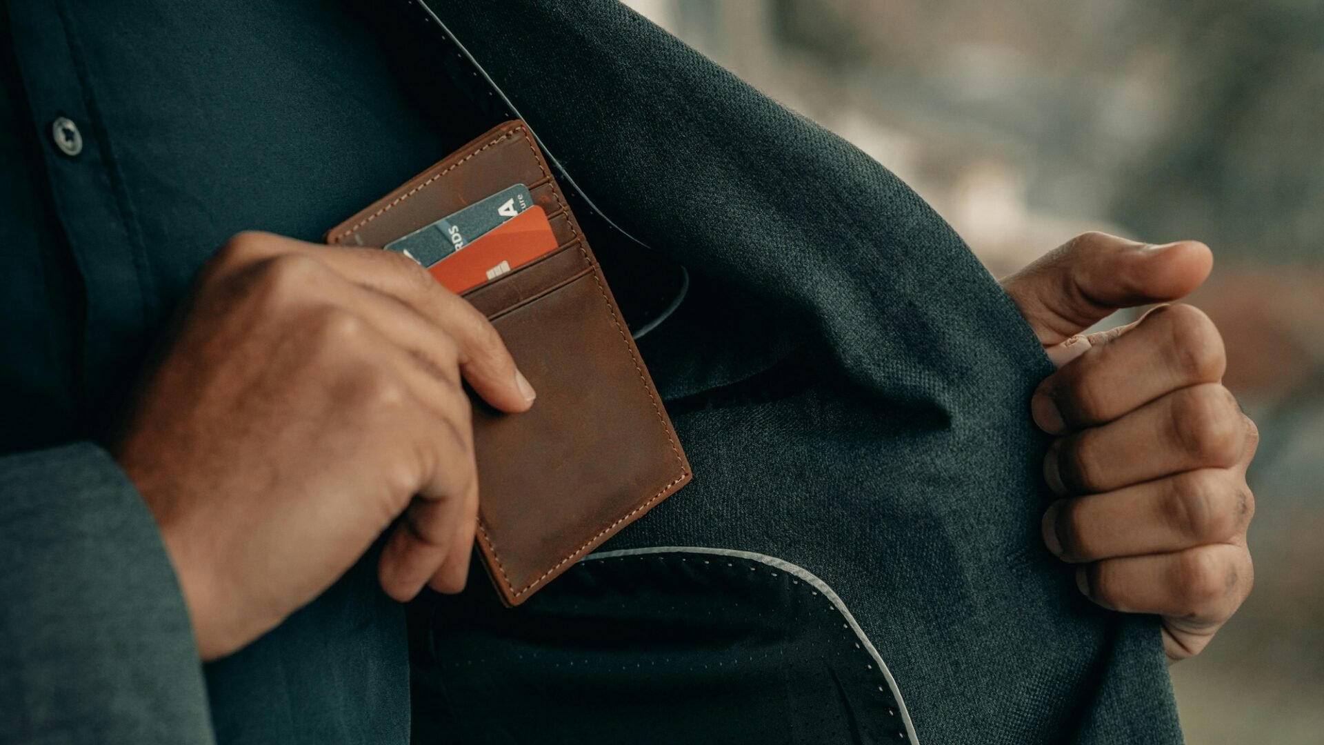 A broker places his wallet in his suit coat pocket, representing his real estate broker salary