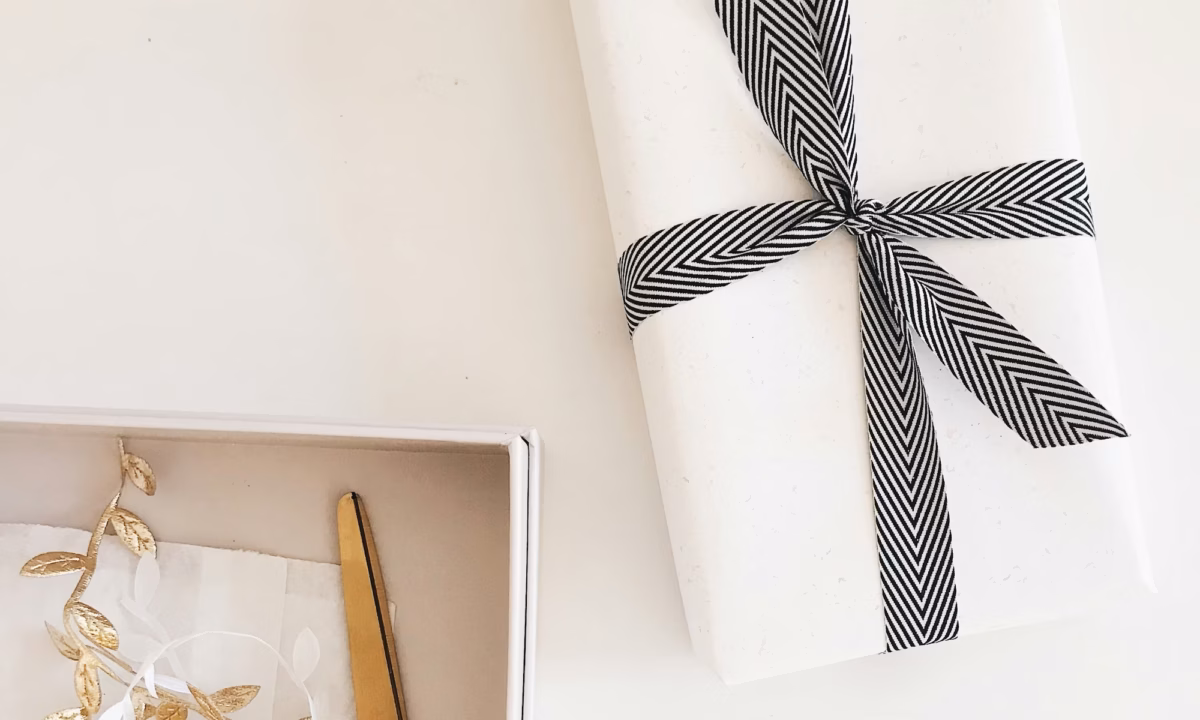 A closing gift for a real estate buyer sits on a realtor's white desk next to a pair of scissors and present decorations