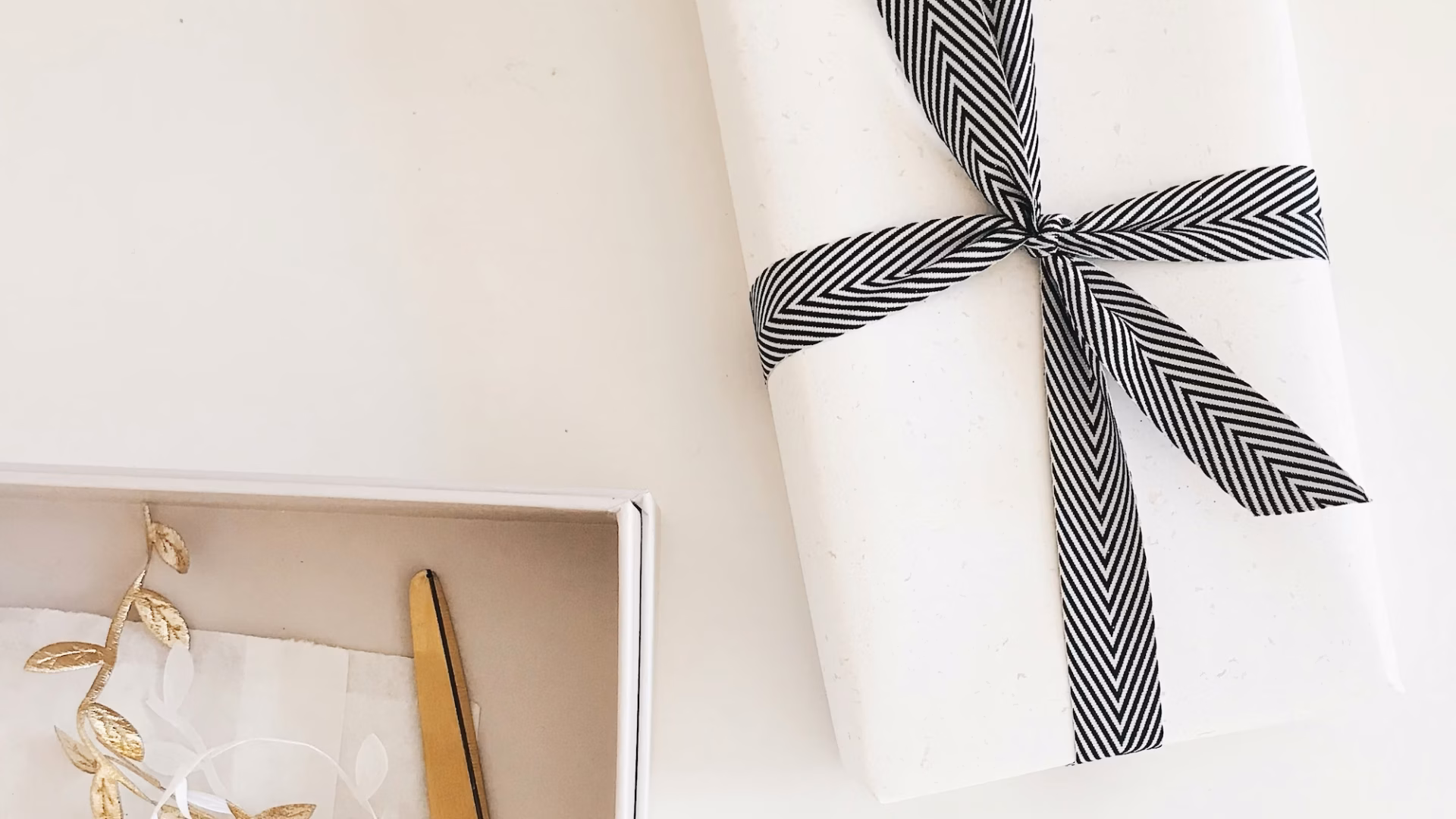 A closing gift for a real estate buyer sits on a realtor's white desk next to a pair of scissors and present decorations