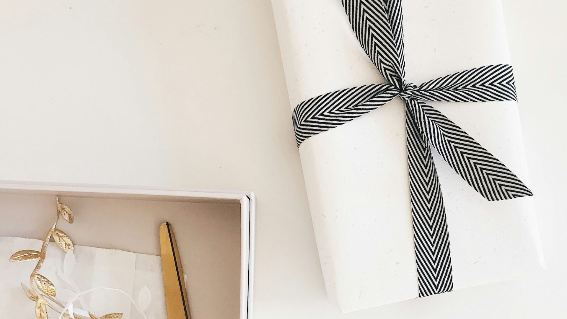 A closing gift for a real estate buyer sits on a realtor's white desk next to a pair of scissors and present decorations