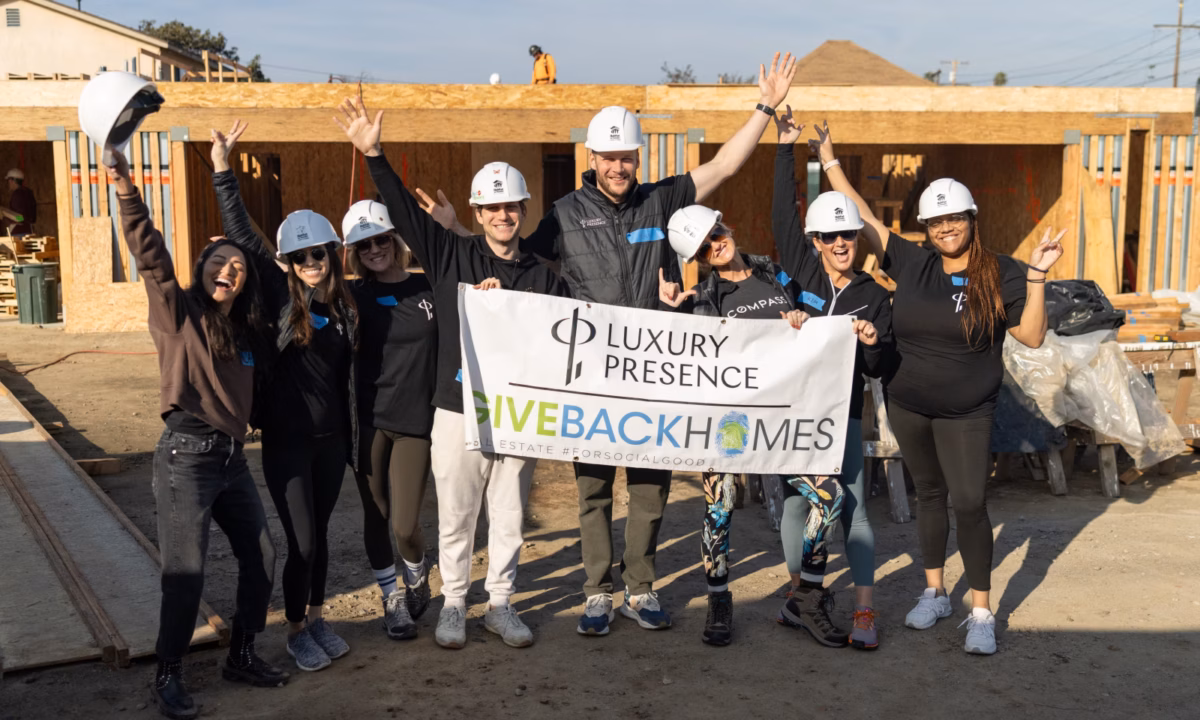 Luxury Presence and Giveback Homes team members holding a sign up at construction site