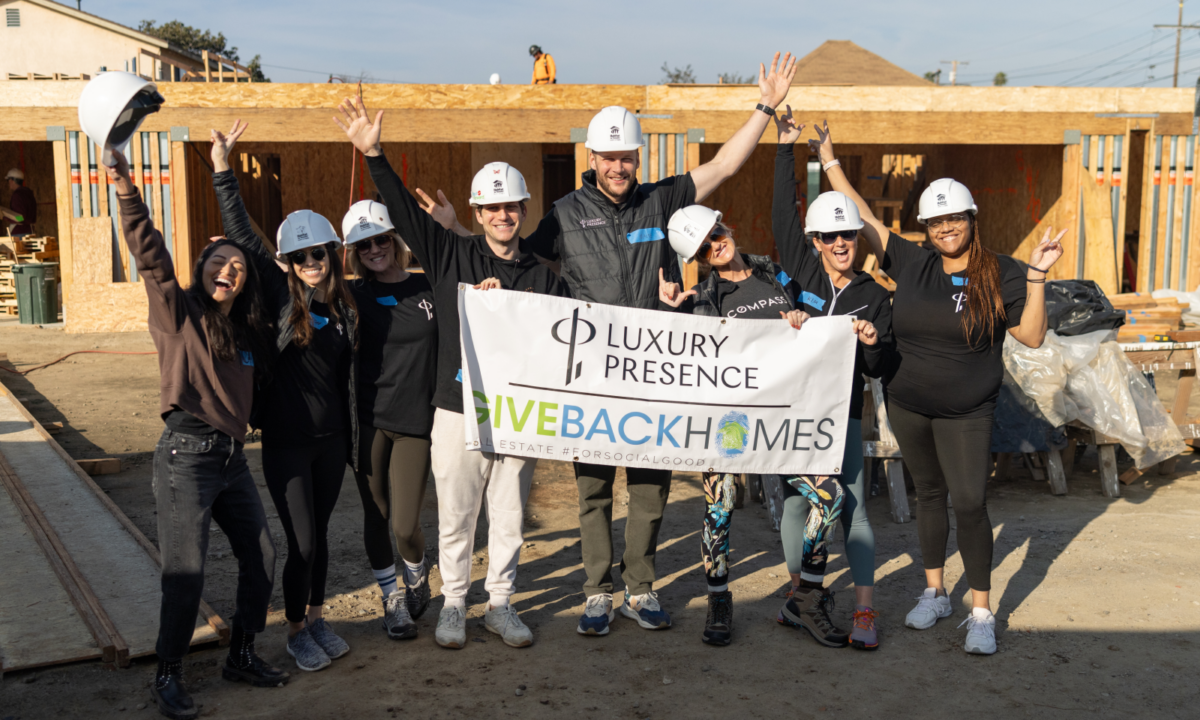 Luxury Presence and Giveback Homes team members holding a sign up at construction site