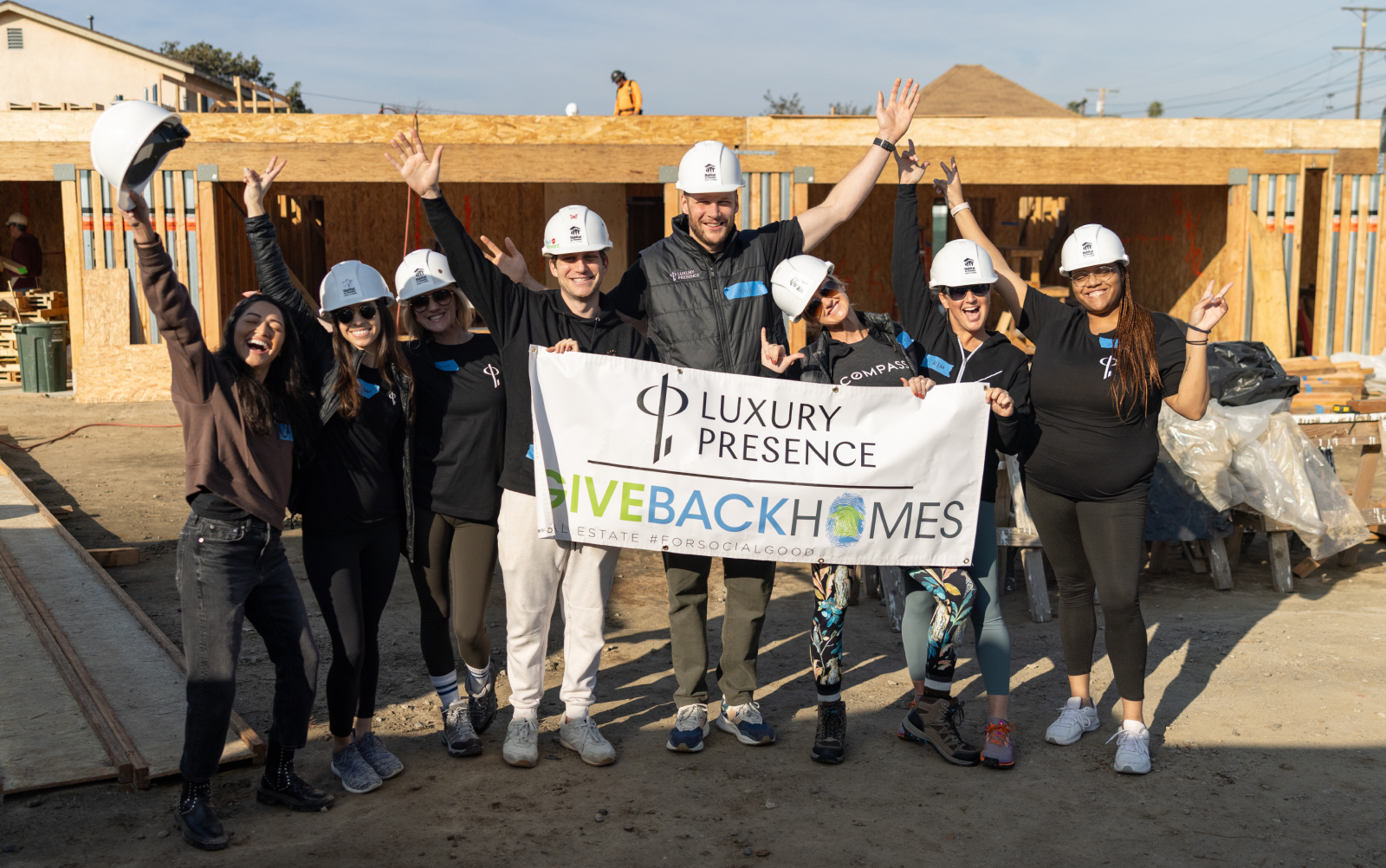 Luxury Presence and Giveback Homes team members holding a sign up at construction site