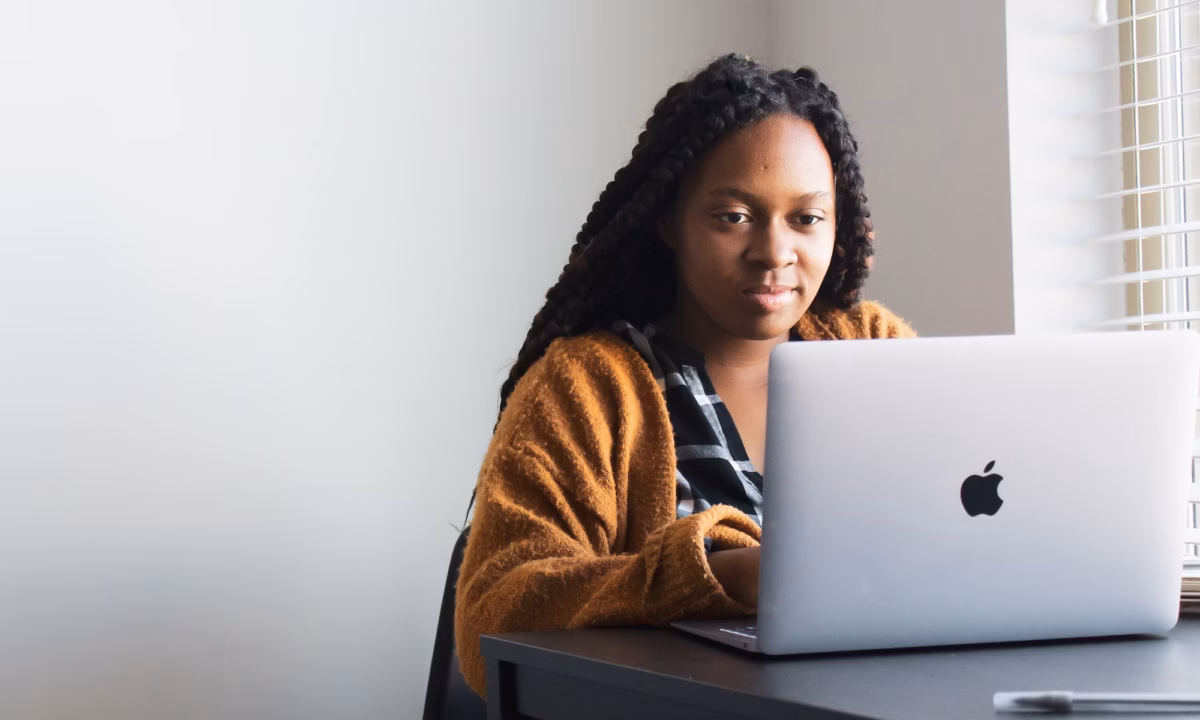 business woman sits at desk in front of a laptop working on her real estate listing presentation