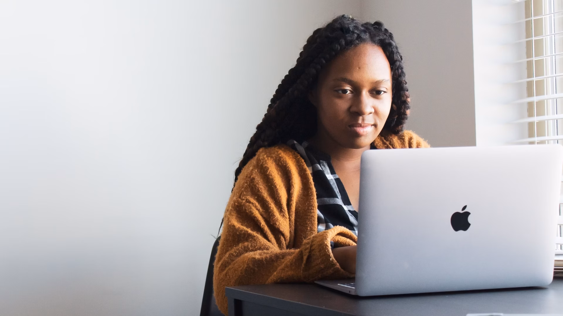 business woman sits at desk in front of a laptop working on her real estate listing presentation