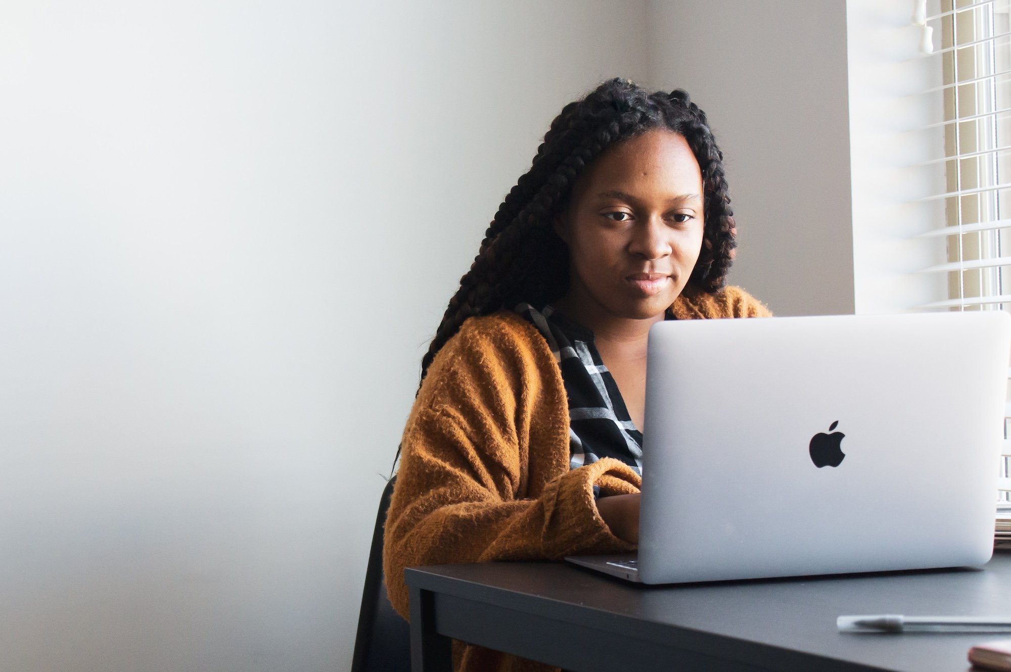 business woman sits at desk in front of a laptop working on her real estate listing presentation