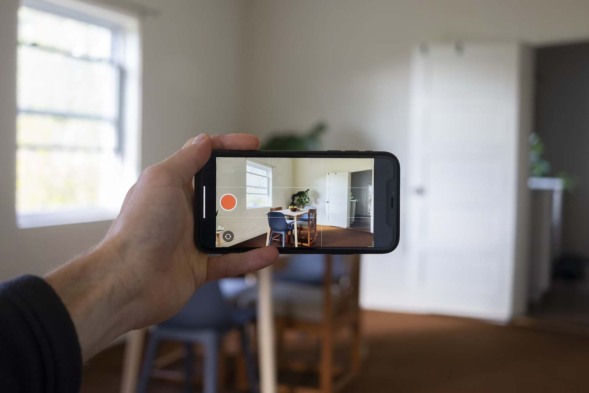 An agent's hand is holding a smartphone filming a listing as part of an effort to create the next viral real estate video