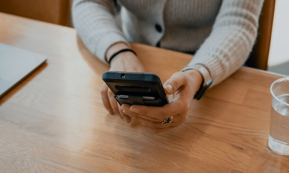 Person sits at wooden desk typing out a message to a real estate chatbot on their smartphone
