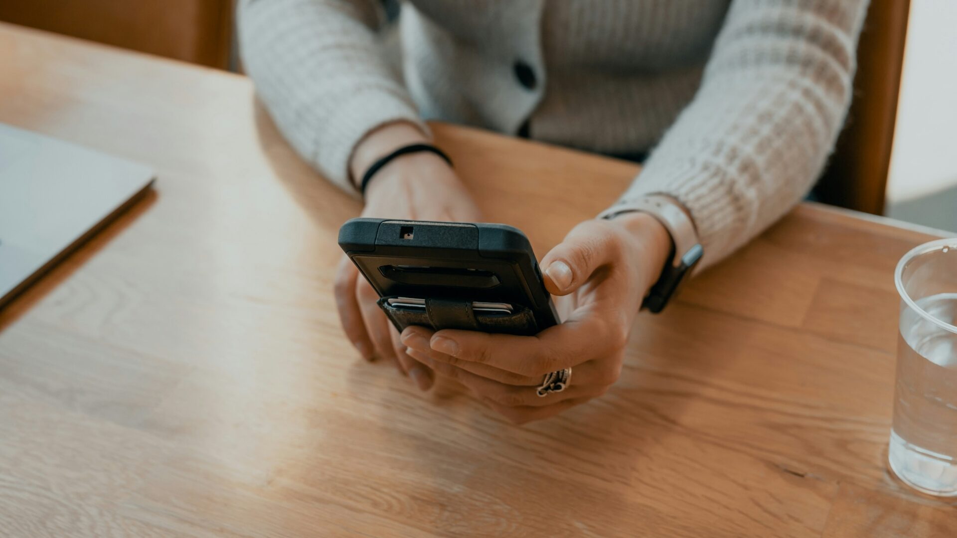 Person sits at wooden desk typing out a message to a real estate chatbot on their smartphone