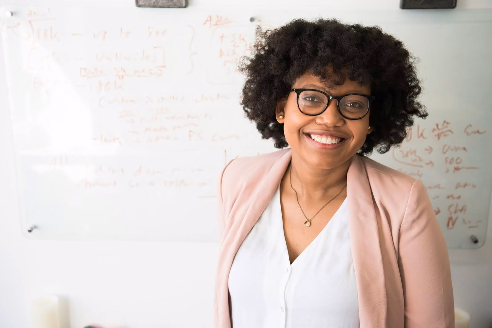 A teacher stands in front of a whiteboard instructing students on how to become a real estate agent