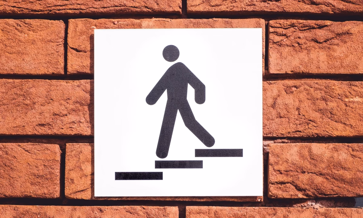 A sign on a brick wall showing a figure descending stairs as a metaphor for real estate lead magnets helping prospects move down the sales funnel