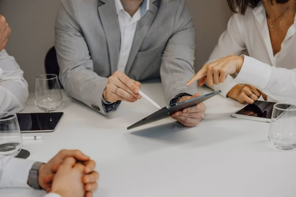 A real estate agent sits with clients pointing to a tablet with a stylus, demonstrating a client-centric approach