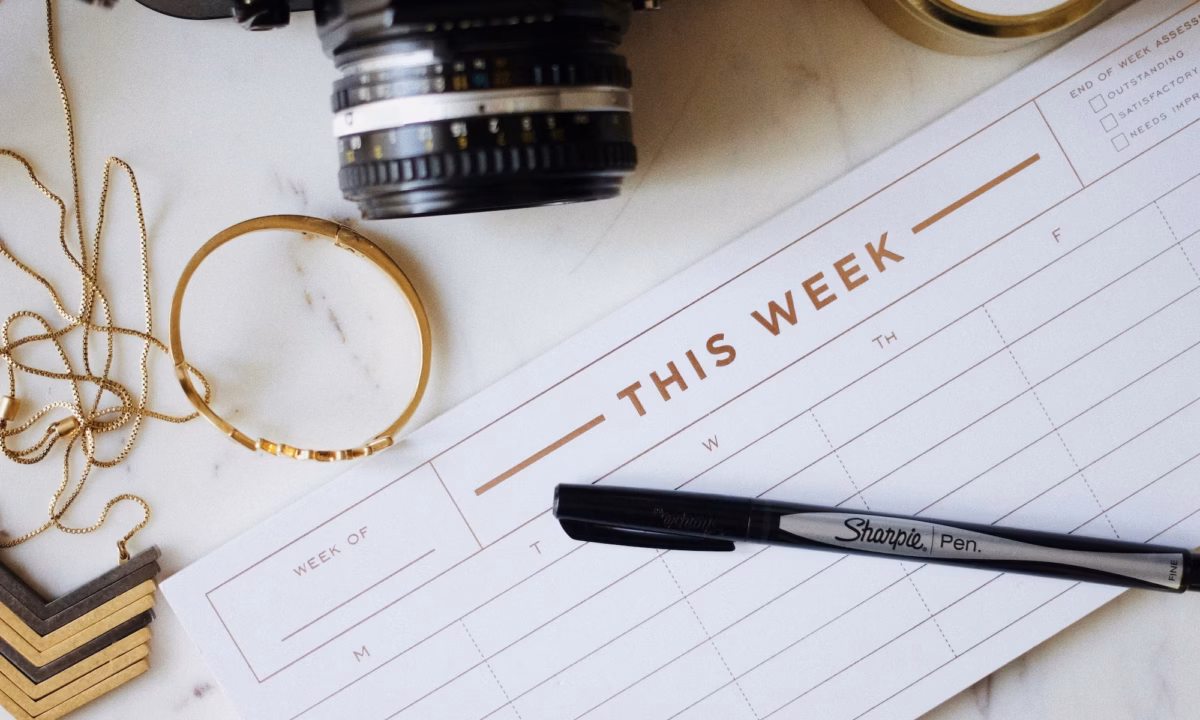 desk with jewelry, a camera and a social media content calendar headlined with "this week"
