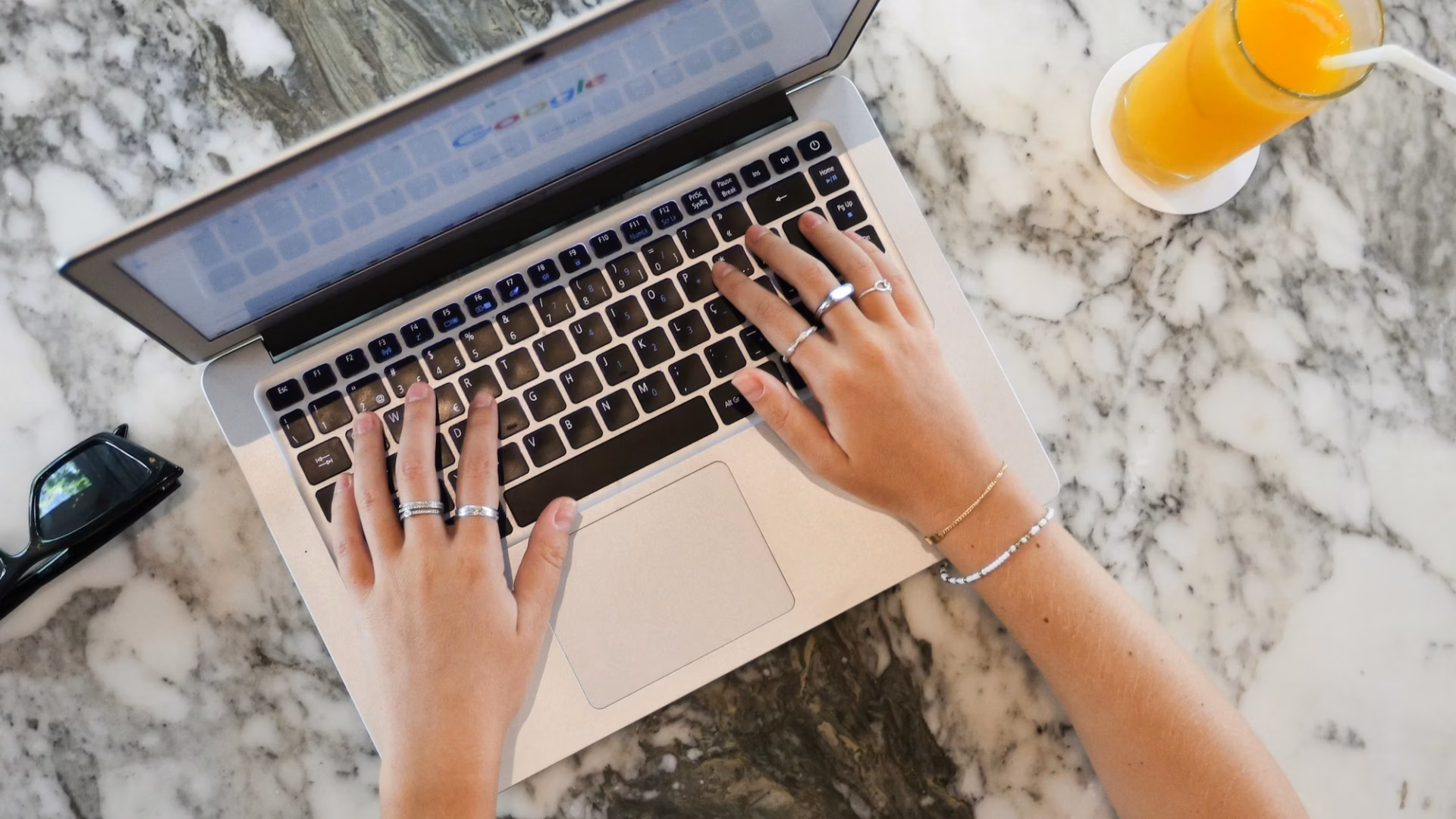 Real estate agent at marble desk with glass of orange juice next to them types of laptop working to Create google business profile