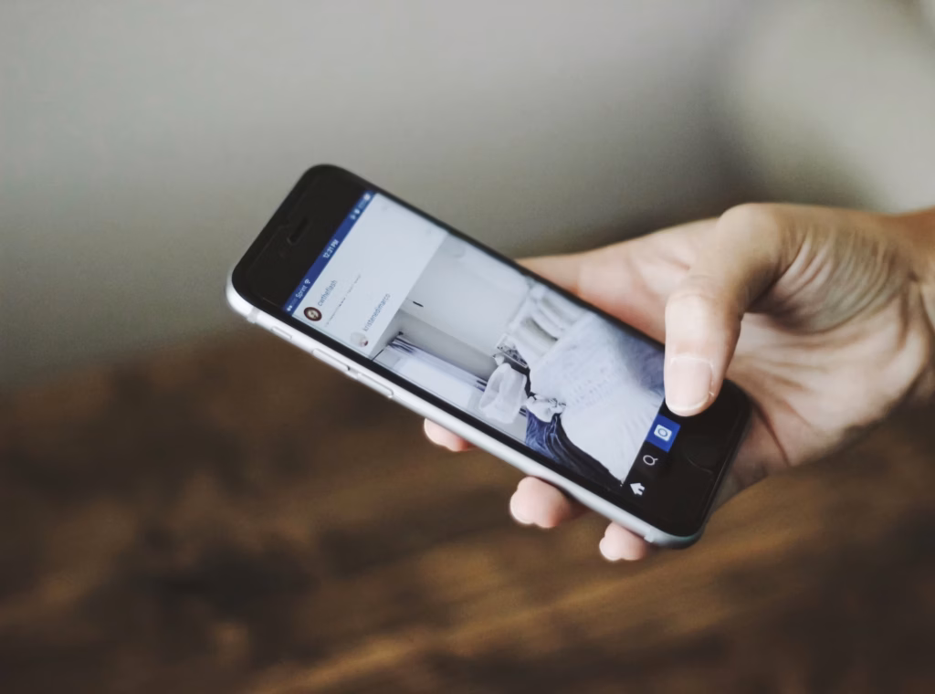 A close up of an agent's hand posting real estate captions for social media from their smartphone