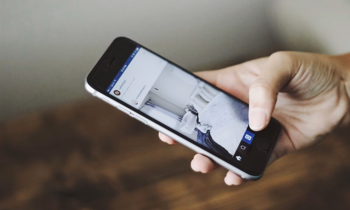 A close up of an agent's hand posting real estate captions for social media from their smartphone