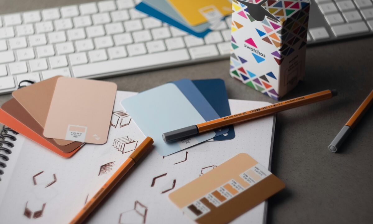 A desk with color cards, pens and sketches on it along with a keyboard, showing the journey to creating the Best real estate brands