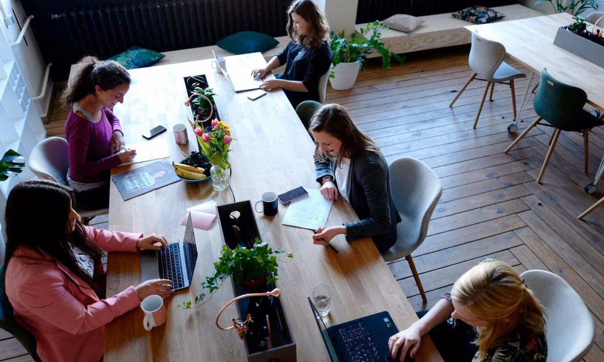 Five agents sit at a long table working on different projects that will help them learn how to succeed as a real estate agent in 2025