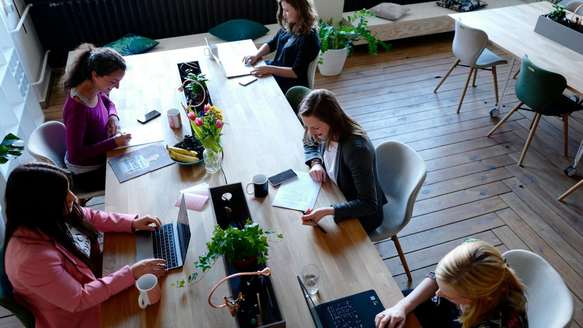 Five agents sit at a long table working on different projects that will help them learn how to succeed as a real estate agent in 2025