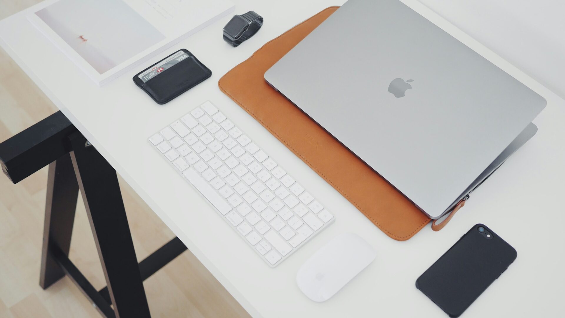 A white desk with a wallet, laptop, smartphone and other items illustrating the average real estate agent salary