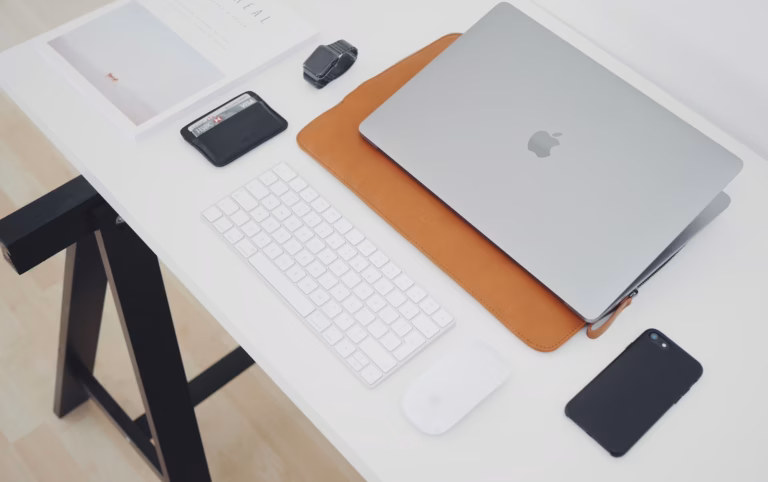 A white desk with a wallet, laptop, smartphone and other items illustrating the average real estate agent salary