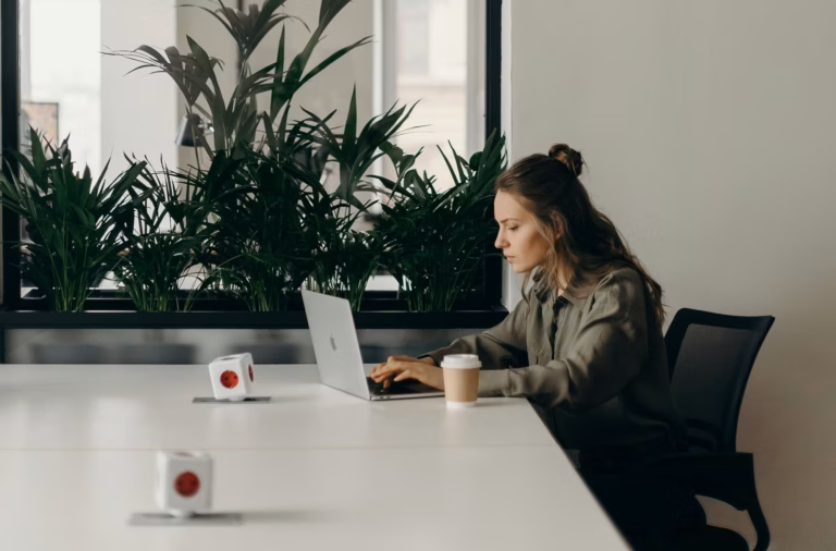 Real estate agent sitting at a white conference table reviewing email marketing laws on a laptop