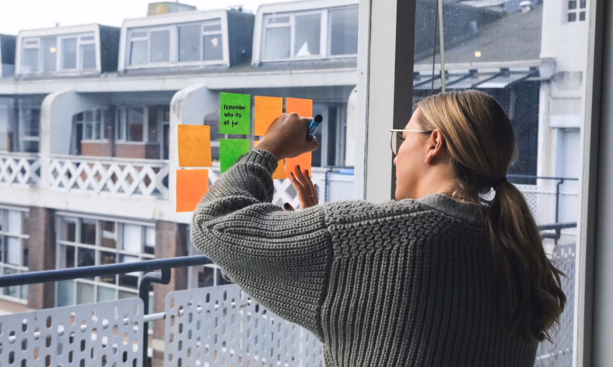An agent writes down real estate newsletter ideas on post-it notes on a sliding glass door overlooking an apartment complex