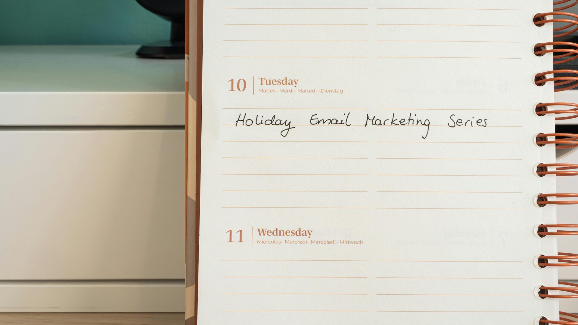 Close-up of a real estate professional's business planner notebook with a memo in it illustrating the best day and time to send email marketing