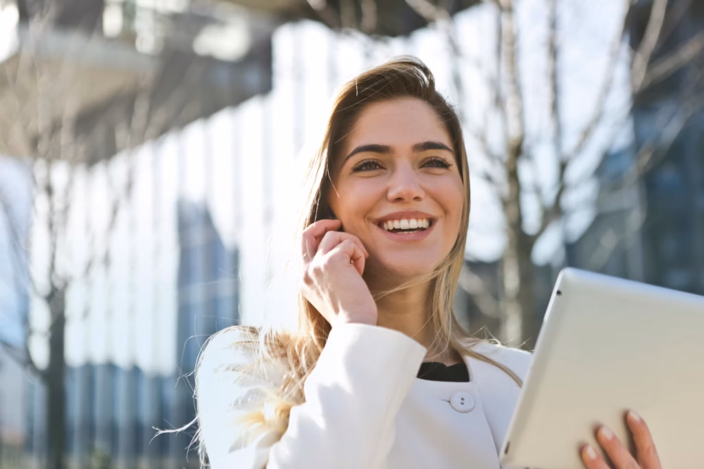 A real estate agent talks to her client on her smartphone while using Luxury Presence's white-labeled app on her tablet