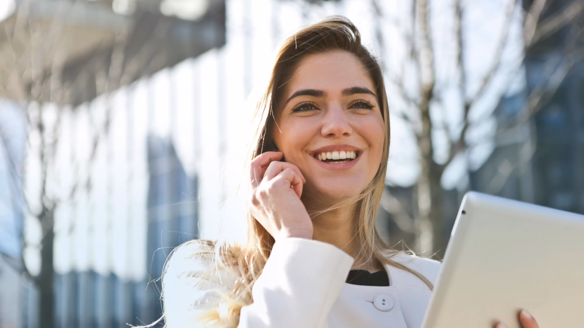 A real estate agent talks to her client on her smartphone while using Luxury Presence's white-labeled app on her tablet