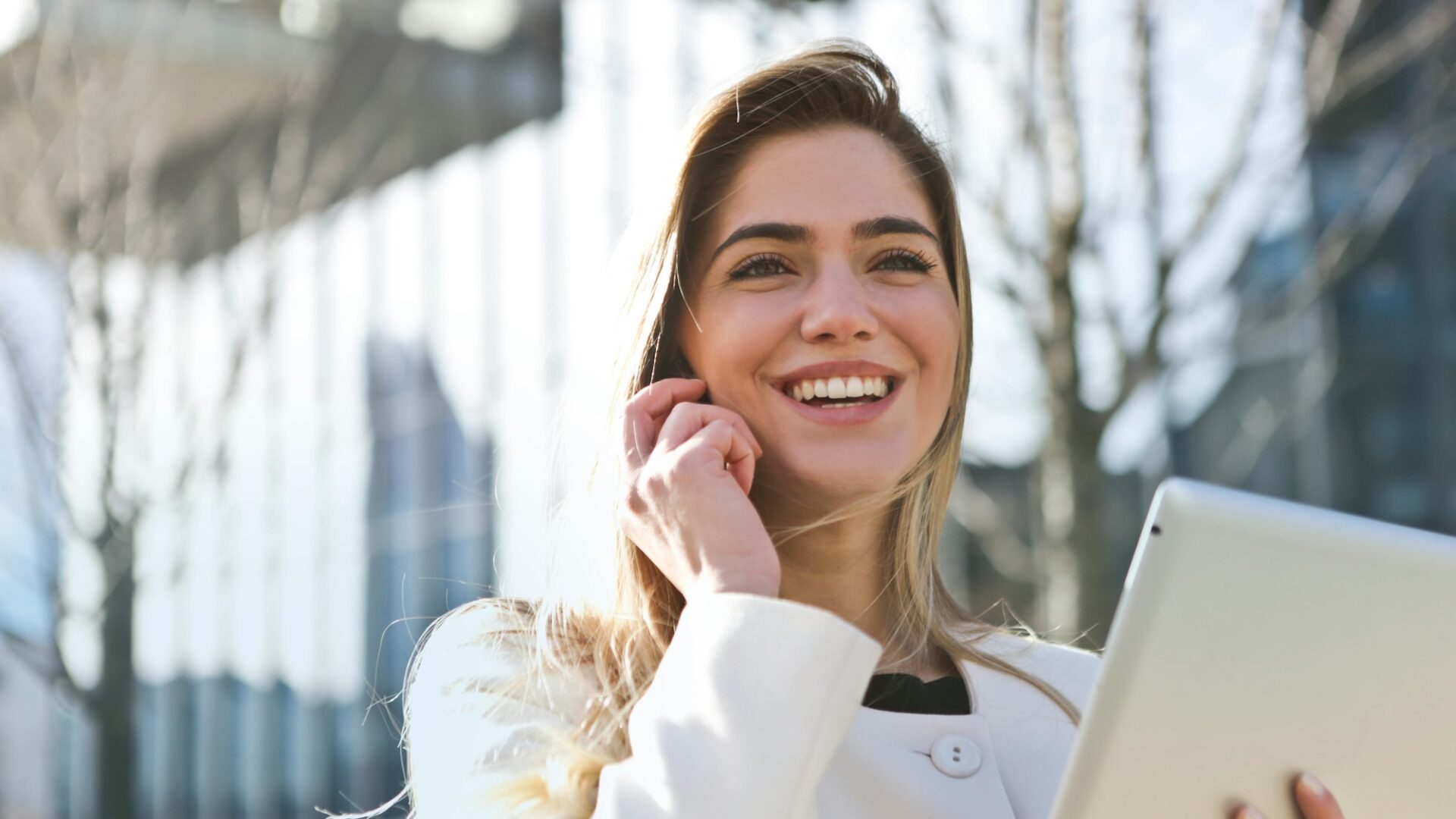 A real estate agent talks to her client on her smartphone while using Luxury Presence's white-labeled app on her tablet