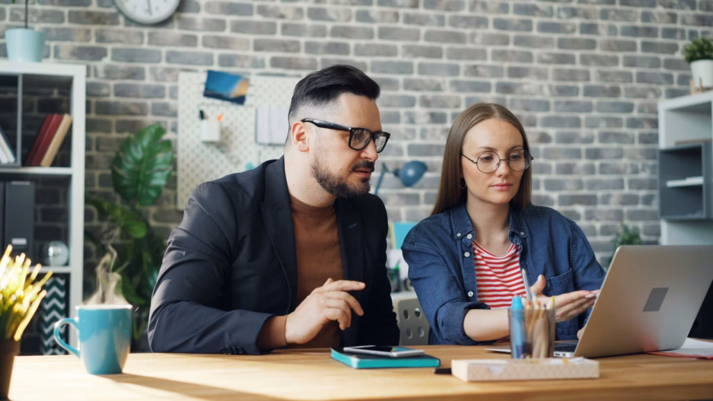 a real estate agent and broker sit in front of a laptop reviewing the ideal email marketing journey to convert leads